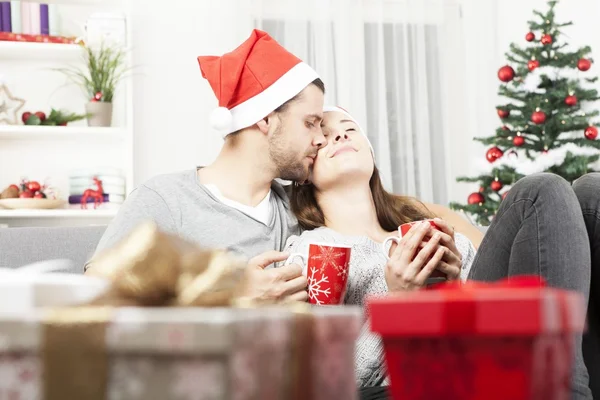 Jonge Kerstmis paar ontspannen op de sofa — Stockfoto