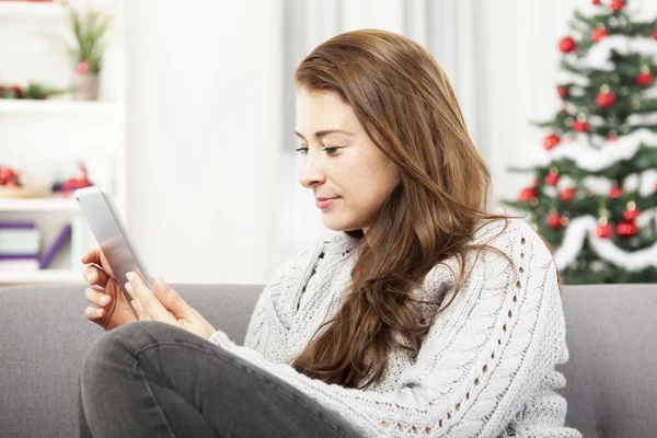 Meisje op bank surfen met de Tablet PC met Kerstmis — Stockfoto