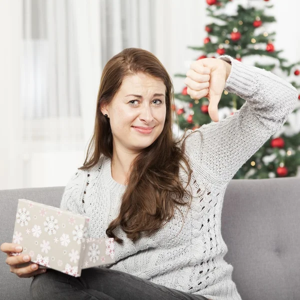 Girl is unhappy about christmas gift and thumb down — Stock Photo, Image