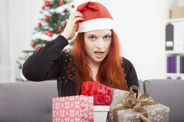 Girl scratching head and holding christmas gifts — Stock Photo, Image