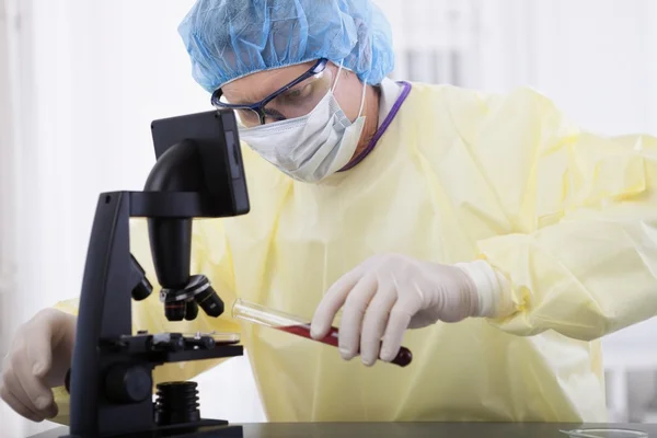 Doctor en equipo protector sosteniendo la muestra de sangre — Foto de Stock