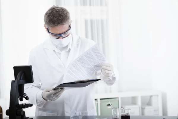 Médico trabalhando com prancheta e sangue — Fotografia de Stock