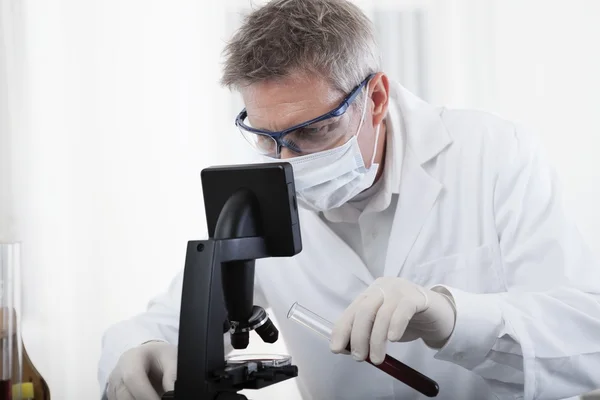 Médico olhando no microscópio e analisar o sangue — Fotografia de Stock