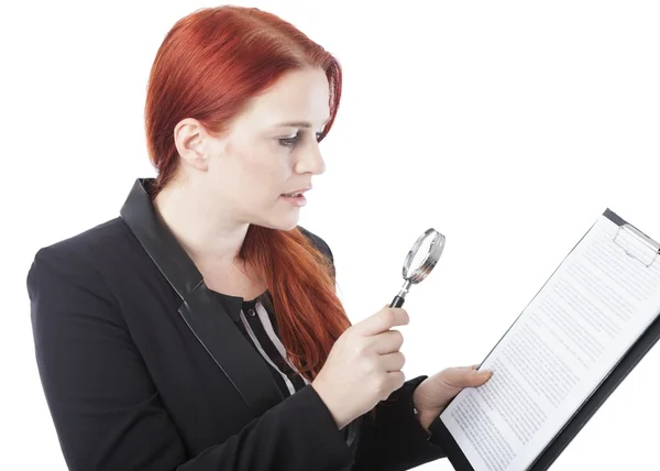 Молодая женщина читает документ с увеличительным стеклом — стоковое фото