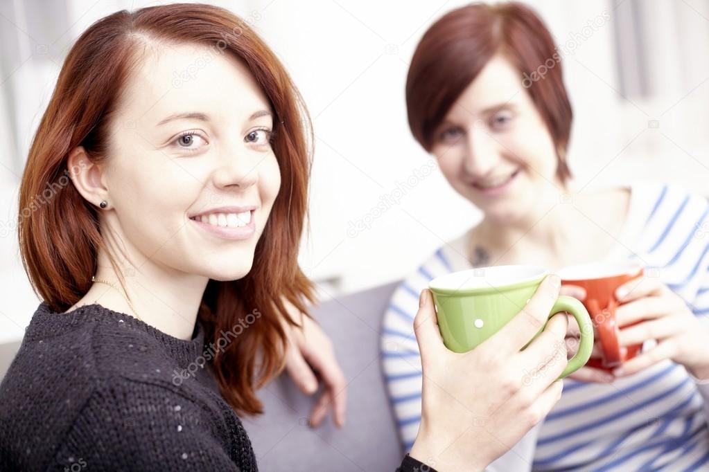 Two happy female friends with coffee cups 
