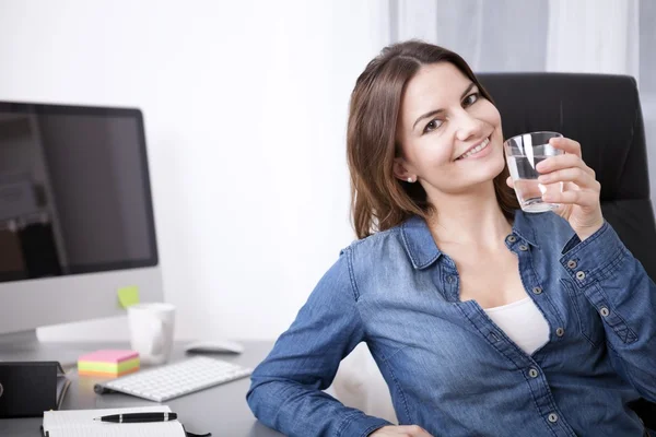 Bürofrau auf ihrem Stuhl mit einem Glas Wasser — Stockfoto