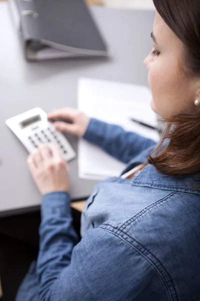 Businesswoman doing calculations at her desk — Stock Photo, Image