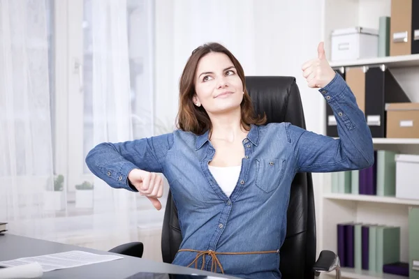 Nachdenkliche Bürofrau zeigt Daumen nach oben und unten — Stockfoto