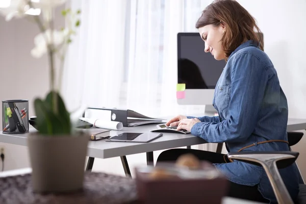 Ocupada jovem empresária sentada em sua mesa de trabalho — Fotografia de Stock