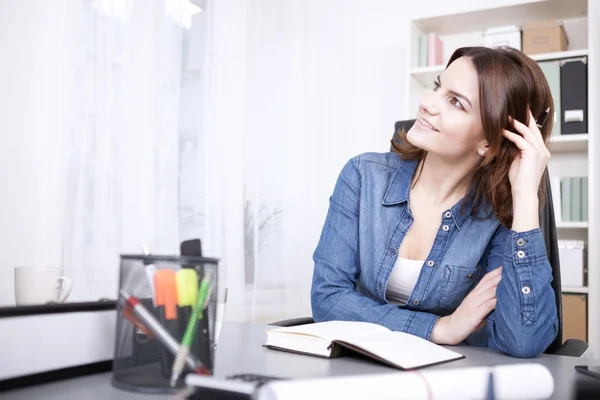 Glückliche nachdenkliche Bürofrau, die sich auf den Tisch lehnt — Stockfoto