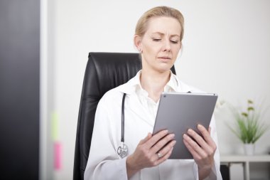 Tablet ekranında ciddi görünümlü kadın klinisyen