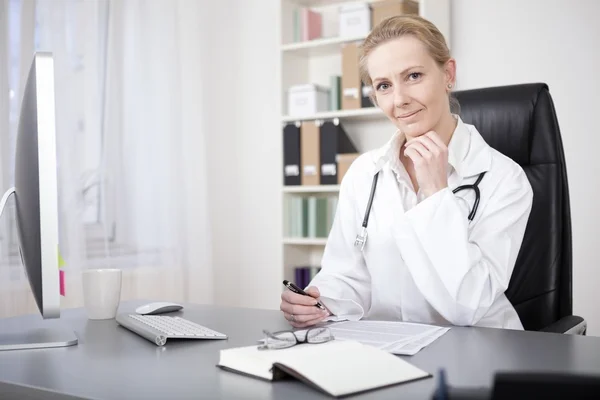 Doctora en su mesa con lápiz y papel — Foto de Stock