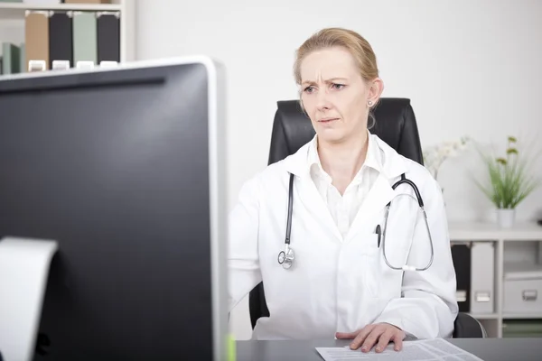 Médecin féminin sérieux regardant moniteur d'ordinateur — Photo