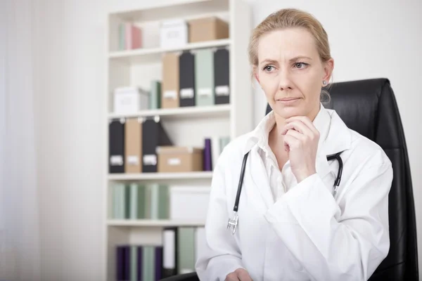 Zamyšlená žena doktor s rukou na bradě — Stock fotografie