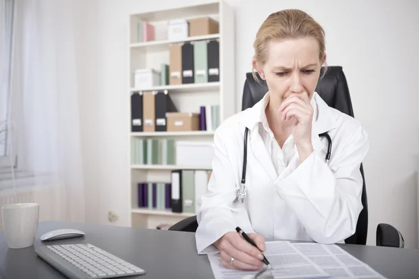 Médecin sérieux lisant des documents sur la table — Photo