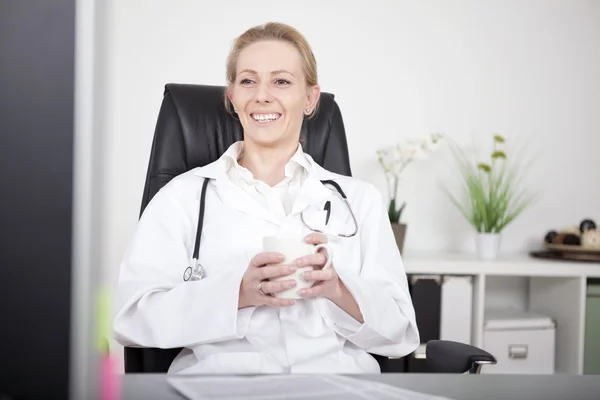 Docteur heureux sur sa chaise avec une tasse de café — Photo