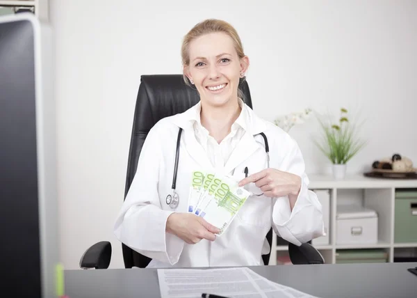 Happy Female Doctor Holding a Fan of 100 Bills — Stock Photo, Image