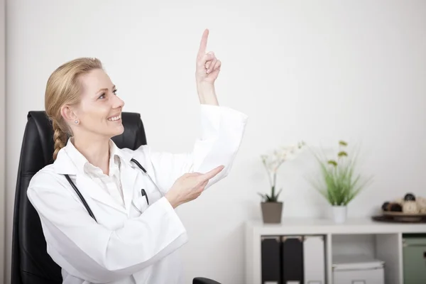 Mujer doctora señalando y mirando hacia arriba a la derecha —  Fotos de Stock