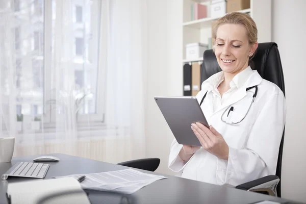 Szczęśliwa kobieta lekarz za pomocą jej urządzenia typu Tablet — Zdjęcie stockowe
