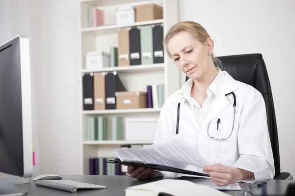 Donna medico lettura rapporti medici presso il suo ufficio — Foto Stock