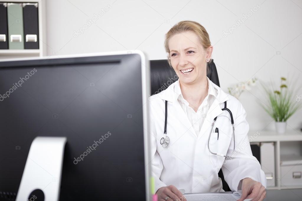 Happy Female Doctor Looking at her Computer Screen