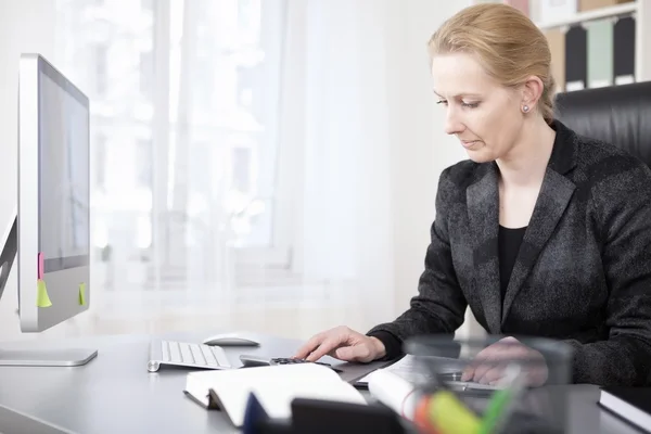 Happy affärskvinna beräkningen av vid sitt arbetsbord — Stockfoto