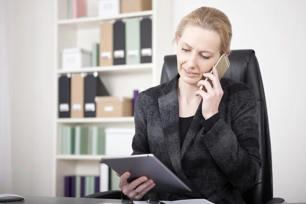 Directie houden een Tablet terwijl bellen op telefoon — Stockfoto