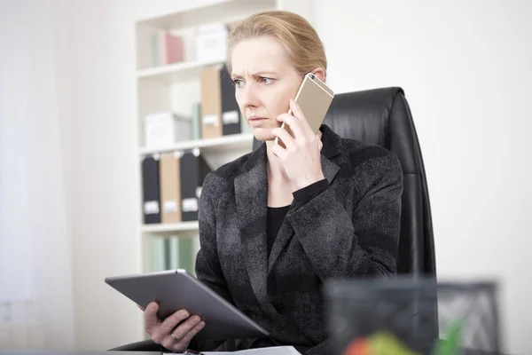 Nadenkend uitbaatster met Tablet bellen op telefoon — Stockfoto