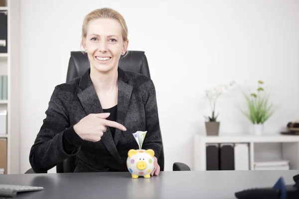 Empresária apontando para Piggy Bank com dinheiro — Fotografia de Stock