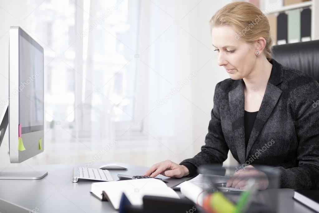 Happy Businesswoman Calculating at her Worktable