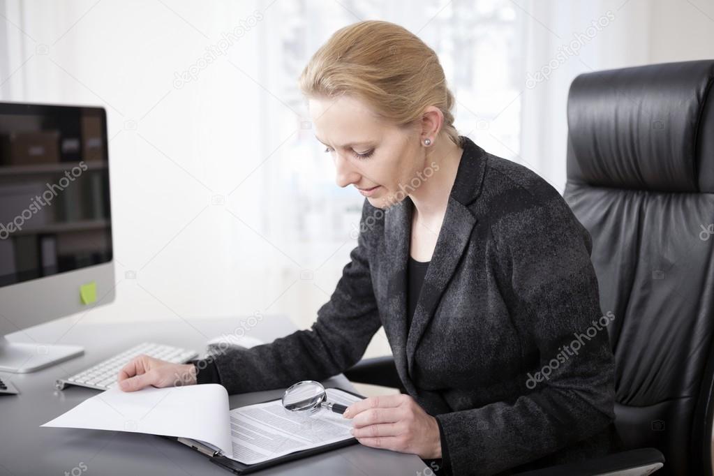 Manageress Scanning Papers with Magnifying Glass