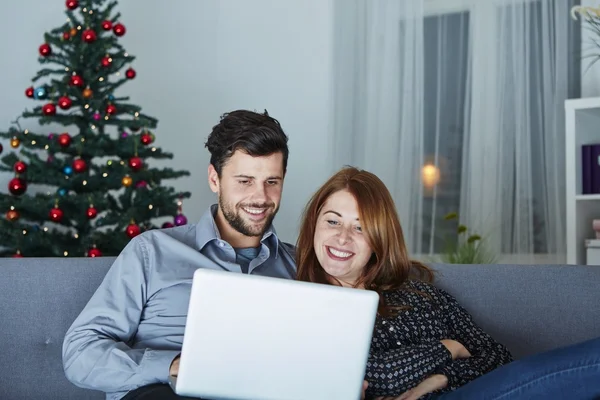 Feliz pareja mira en el ordenador portátil PC para Navidad —  Fotos de Stock