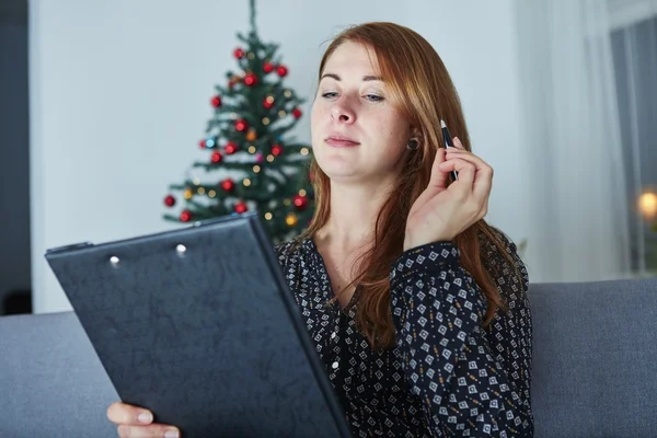 Mujer piensa en la lista de Navidad wih en el sofá —  Fotos de Stock