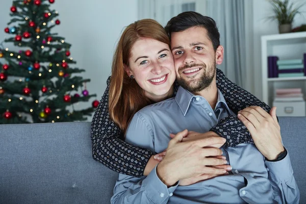 Young happy couple hug on sofa — Stock Photo, Image
