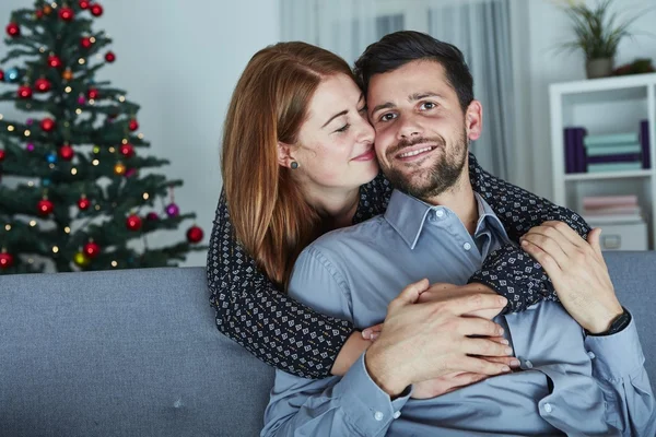 Unga lyckliga paret kram på soffa — Stockfoto