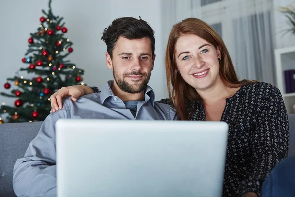 Feliz pareja mira en el ordenador portátil PC para Navidad —  Fotos de Stock