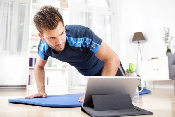 Hombre haciendo planchar mientras mira la película en la tableta —  Fotos de Stock