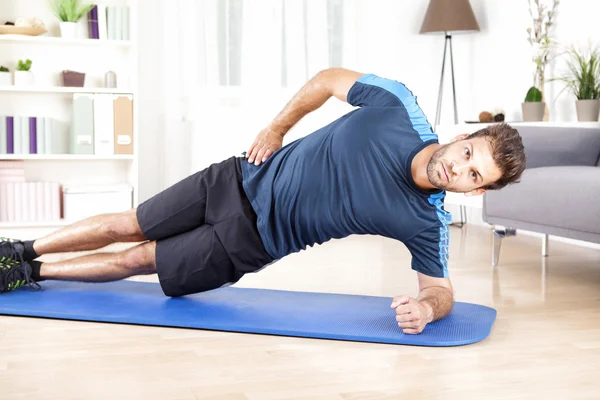 Uomo sano che fa esercizio tavola laterale su un tappeto — Foto Stock