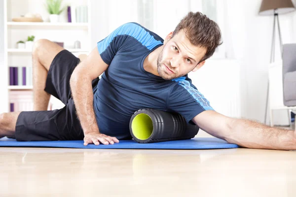 Homme athlétique utilisant le rouleau de mousse dans l'exercice — Photo