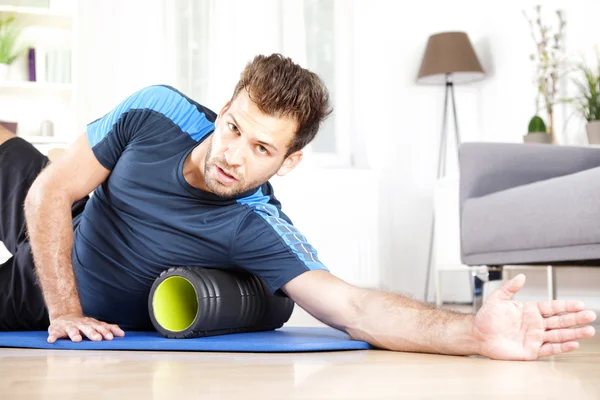 Knappe jongen liggen aan kant met schuim Roller — Stockfoto