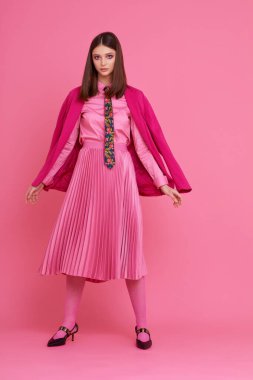 Mor ceketli, pembe etekli ve gömlekli manken. Stüdyo çekimi.