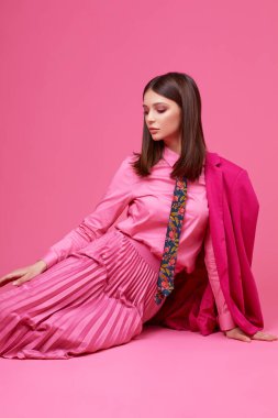 Mor ceketli, pembe etekli ve gömlekli manken. Stüdyo çekimi.
