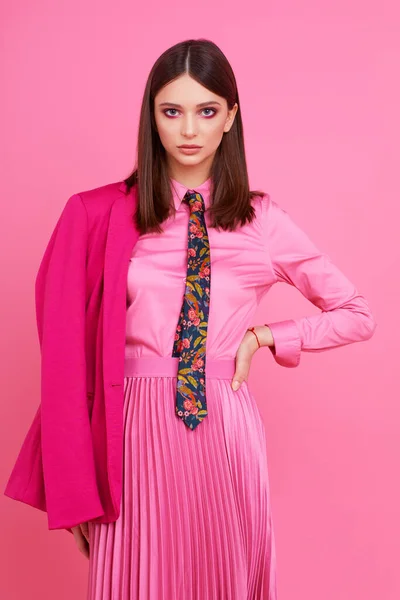 Fashion model in magenta jacket, pink skirt and shirt. Studio shot.