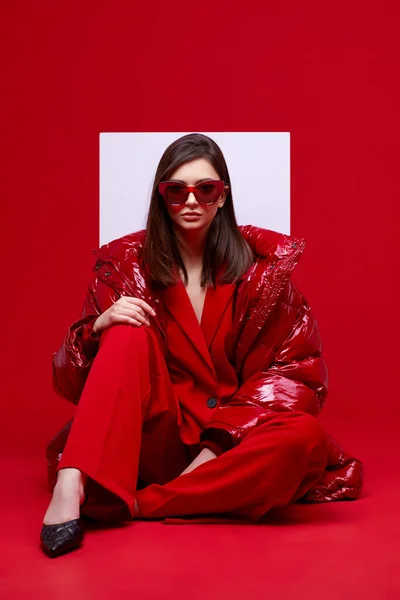 穿着红色西服 羽绒服和太阳镜的时装模特 工作室拍摄 — 图库照片