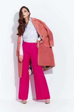 Genç ve zarif bir kadının yüksek moda portresi. Mercan palto, mor pantolon, beyaz bluz. Beyaz arkaplan