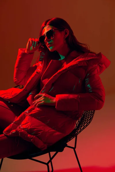 穿着红色羽绒服的优雅时髦女人的时尚肖像 霓虹灯 太阳镜 工作室拍摄 — 图库照片