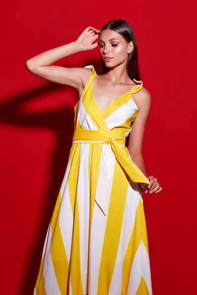 Portret Młodej Eleganckiej Kobiety Żółta Sukienka Białymi Paskami Czerwone Tło — Zdjęcie stockowe