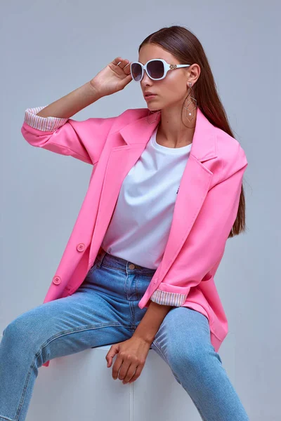 年轻优雅女子的时尚肖像 粉色夹克 蓝色牛仔裤 太阳镜工作室拍摄 — 图库照片