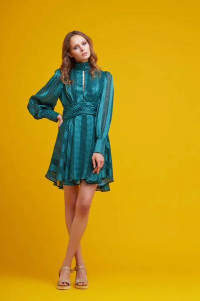 緑のドレスの美しい若い女性 黄色の背景 ファッションスタジオショット — ストック写真