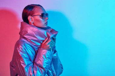 Güneş gözlüklü zarif bir kadının moda portresi. Gümüş rengi ceketli, neon ışıklı